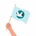 Hand holding a flag with white dove in flight holding an Olive Branch on Earth planet background. Peace pigeon Royalty Free Stock Photo