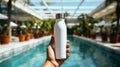 Hand holding flask in front of swimming pool ai generated bottle mockup