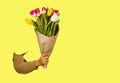 Hand holding flowers over yellow background. Bouquet of tulips for Birthday, Happy mothers or Valentines day. Royalty Free Stock Photo