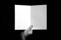 Hand holding folded blank sheet of paper against black background Royalty Free Stock Photo