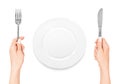 Hand holding fork and knife with plate