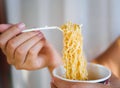 Hand holding fork to eat spicy instant noodles in cup