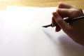 Hand holding a fountain pen on blank white paper with copy space Royalty Free Stock Photo