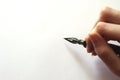 Hand holding a fountain pen on blank white paper with copy space Royalty Free Stock Photo