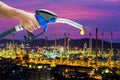 Hand holding a fuel nozzle with refinery background