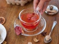 A hand holding a full teacup. Red tea with spices on a blurred wooden background. A traditional red tea for breakfast. Royalty Free Stock Photo