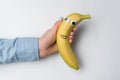 Hand holding fun banana with Googly eyes and smile on white background Royalty Free Stock Photo