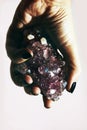 Hand holding gemstone Amethyst closeup with rock Quartz crystals.