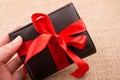 Hand holding a wallet wrapped with ribbon