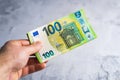 Hand holding and giving one hundred 100 euro banknotes. Money in man hands on gray background Royalty Free Stock Photo