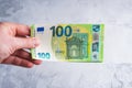 Hand holding and giving one hundred 100 euro banknotes. Money in man hands on gray background Royalty Free Stock Photo