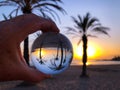 Hand holding glass ball, beach to sea view at dawn