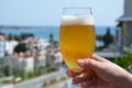 Hand holding a glass of beer in beach tropical sea background. vacation holiday concept