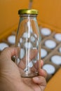 The hand holding a glass bottle with gold bottle caps in a cardboard box, Packaging concept.