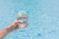 Hand holding a glass of cold drinking water with a piece of lemon