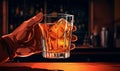 Hand holding a glass filled with alcohol on a bar in a nightclub or pub. Royalty Free Stock Photo