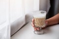 A hand holding a glass of hot latte coffee on wooden table Royalty Free Stock Photo