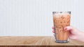 Hand holding the glass iced coffee on wooden table on white background, Ice latte coffee