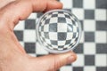 hand holding a glass lens ball over a marble chess board, soft focus close up Royalty Free Stock Photo