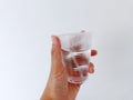 hand holding glass mineral water with half the contents left,isolated on a white background