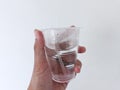 hand holding glass mineral water with half the contents left,isolated on a white background
