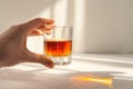 Hand holding a glass of Sazerac cocktail with a white background