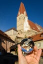 Hand holding glass sphere in front of church