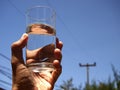 Hand holding a glass of water against a blue sky Royalty Free Stock Photo