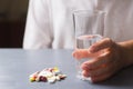 Hand holding glass of water near colorful different capsules and pills on table Royalty Free Stock Photo