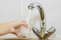 Hand holding a glass of water poured from the kitchen faucet Royalty Free Stock Photo