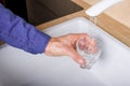 Hand holding a glass of water poured from the kitchen faucet Royalty Free Stock Photo