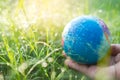 Hand holding Globe or earth on fresh dew grass with sunlight.orld earth day, Royalty Free Stock Photo