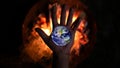 Hand holding a globe in front of a fire Royalty Free Stock Photo