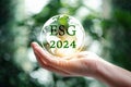 Hand holding globe with 2024 green ESG on nature background. 2024 Green business, environmental social governance sustainability.