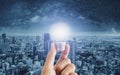 Hand holding glowing light bulb, with futuristic city background Royalty Free Stock Photo