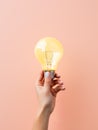 Hand holding a glowing lightbulb against a minimal backdrop, symbolizing the concept of innovative thinking and creativity. Royalty Free Stock Photo