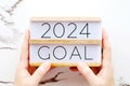 Hands holding 2024 goals wood box over marble background, banner, business new year, aim to success in business Royalty Free Stock Photo