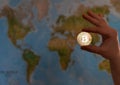 Hand holding gold coin of Bitcoin against map of world. Bitcoin Royalty Free Stock Photo