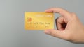 Hand is holding gold color credit card isolated on grey background Royalty Free Stock Photo