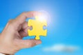 Hand holding gold jigsaw puzzle piece with blue sky sunlight Royalty Free Stock Photo