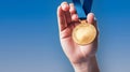 Hand holding gold medal winner on blue background, no number. Generative AI Royalty Free Stock Photo