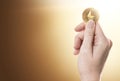 Hand holding a golden Ethereum coin on a gently lit background with copy space.