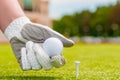 Hand holding a golf ball near the tee Royalty Free Stock Photo