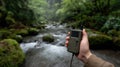 Hand Holding GPS Device in Misty Forest by River Stream for Navigation Royalty Free Stock Photo