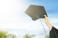 Hand holding graduation hat with blue sky background