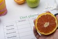 The hand holding the grapefruit over a diet plan Royalty Free Stock Photo