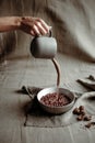 hand holding a gray cup pouring milk into a bowl of chocolate cocoa breakfast