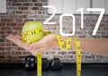 Hand holding green apple wrapped with measuring tape against 2017 Royalty Free Stock Photo