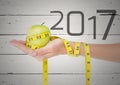 Hand holding green apple wrapped with measuring tape against 2017 Royalty Free Stock Photo