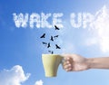 Hand holding green coffee cup with bird and wake up text on sky Royalty Free Stock Photo